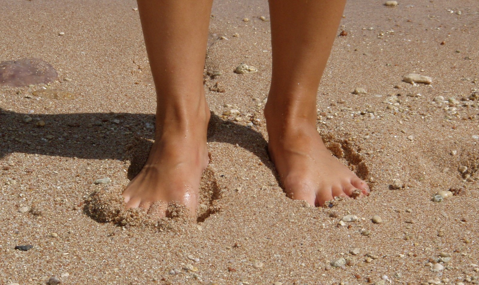 barefoot beachcomber feet on sandy beach and water