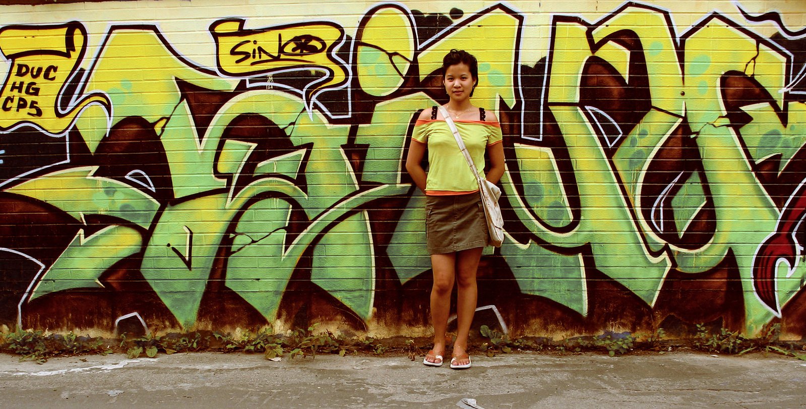 woman standing in front of graffiti covered wall