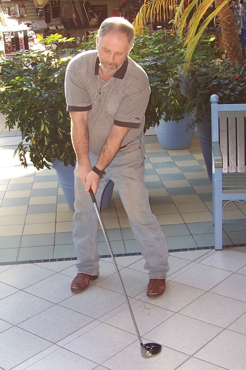 a man in white shirt holding a golf club