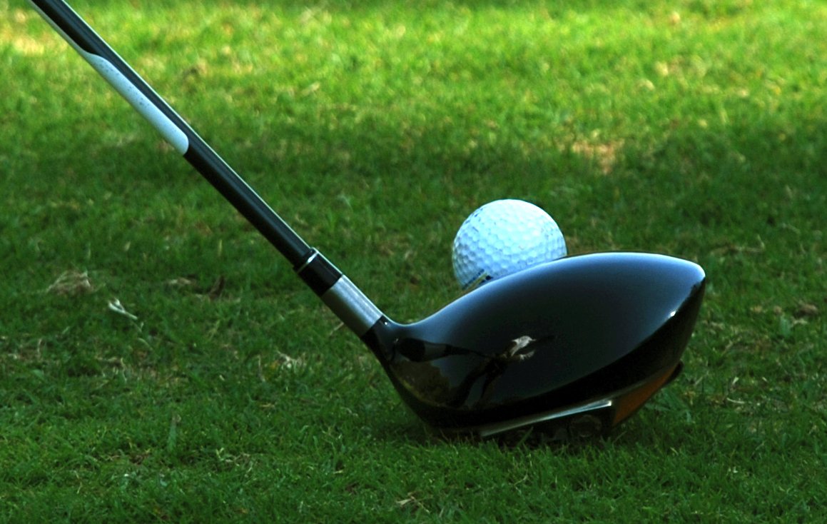 a golf club and a ball sitting on top of the grass