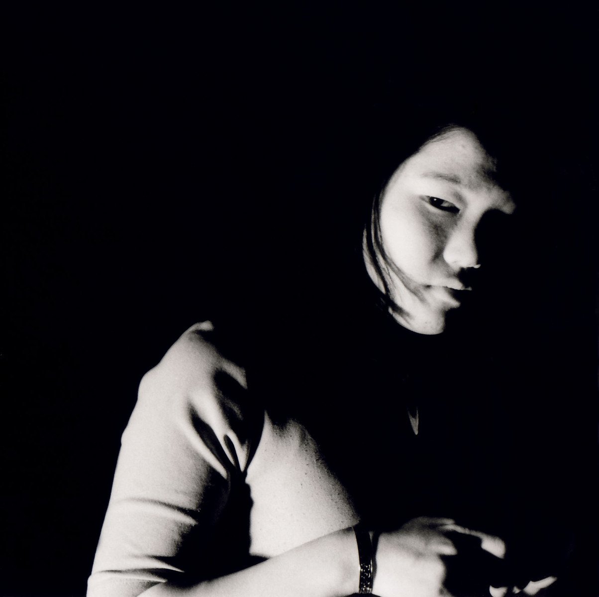 black and white image of woman sitting in the dark