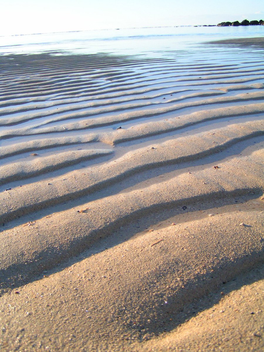 sand moves in a small wave on the beach