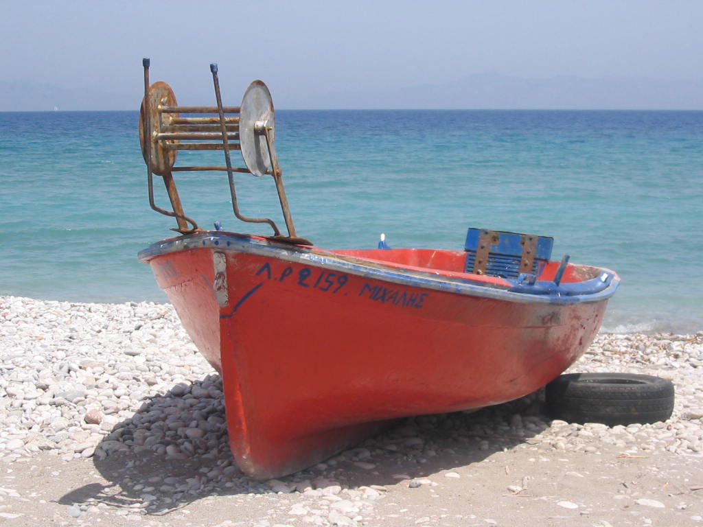 there is an empty red boat on the beach