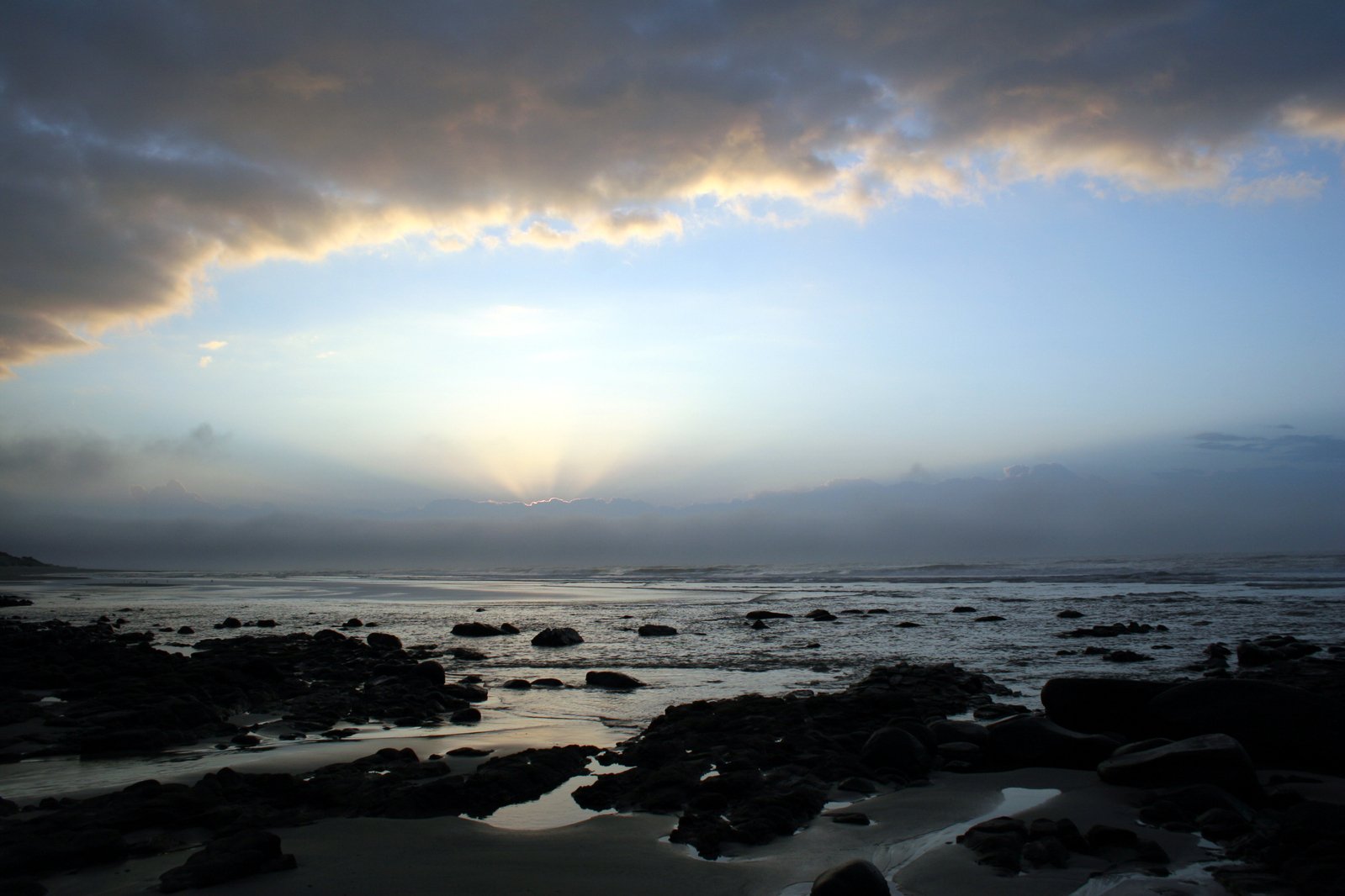 a dark sky is over some water and rocks