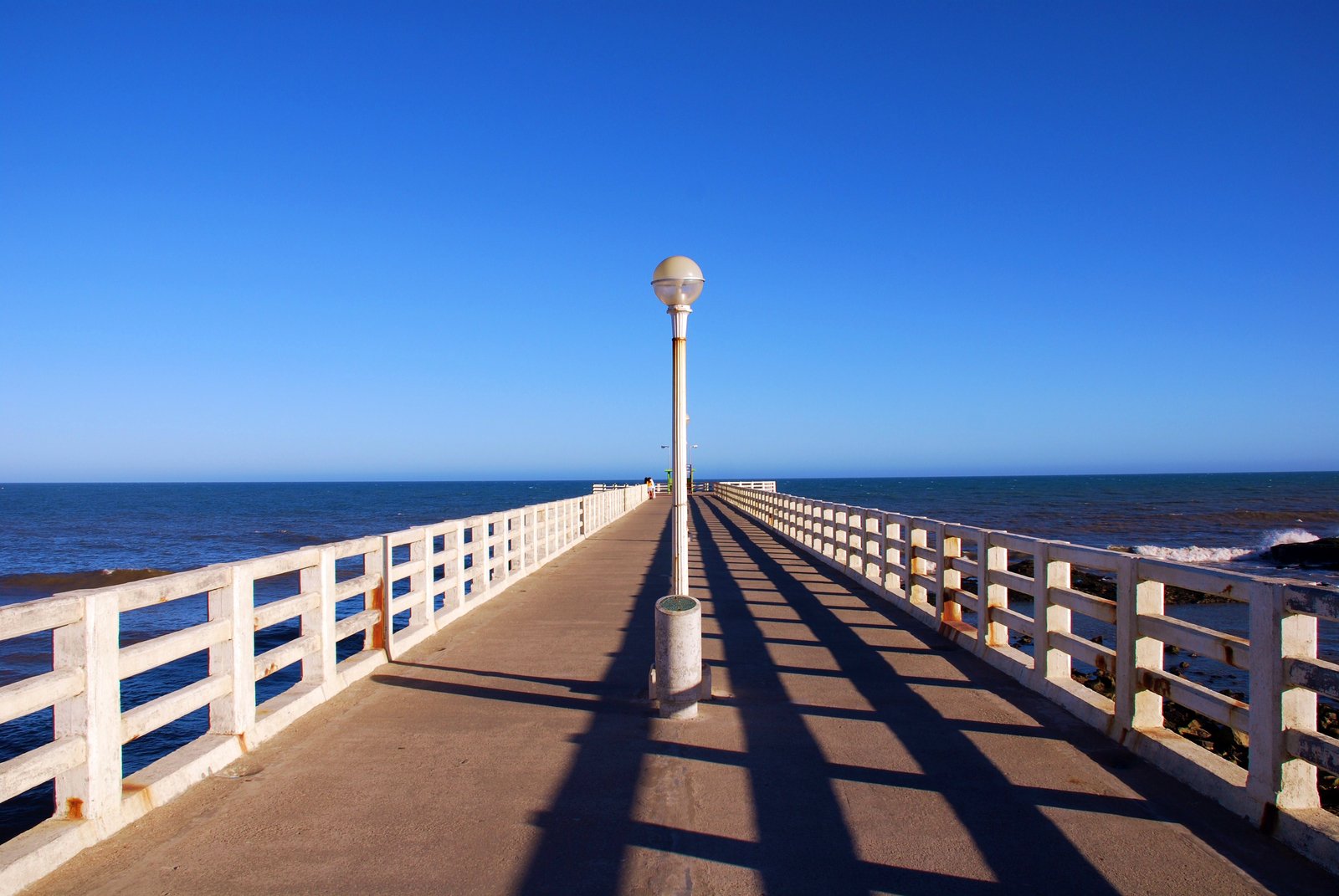 a lamppost in the middle of a pier overlooking the ocean