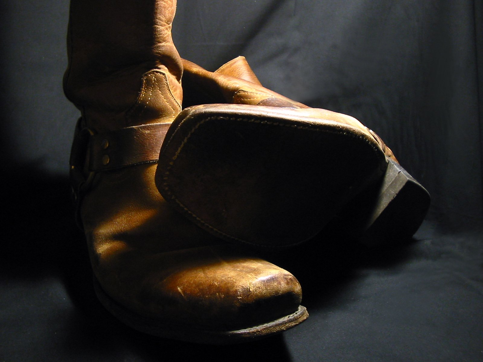 a worn pair of brown boots on a black background