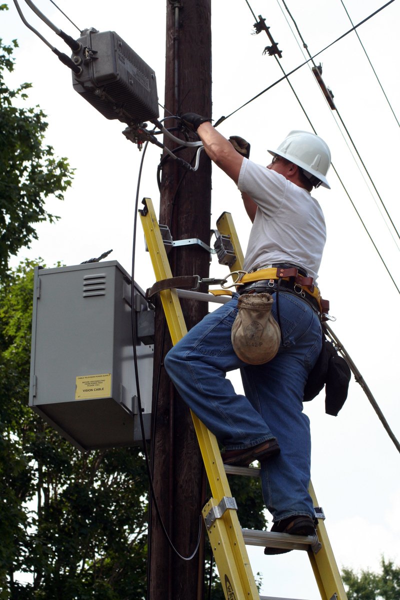 a worker is repairing an electrical pole