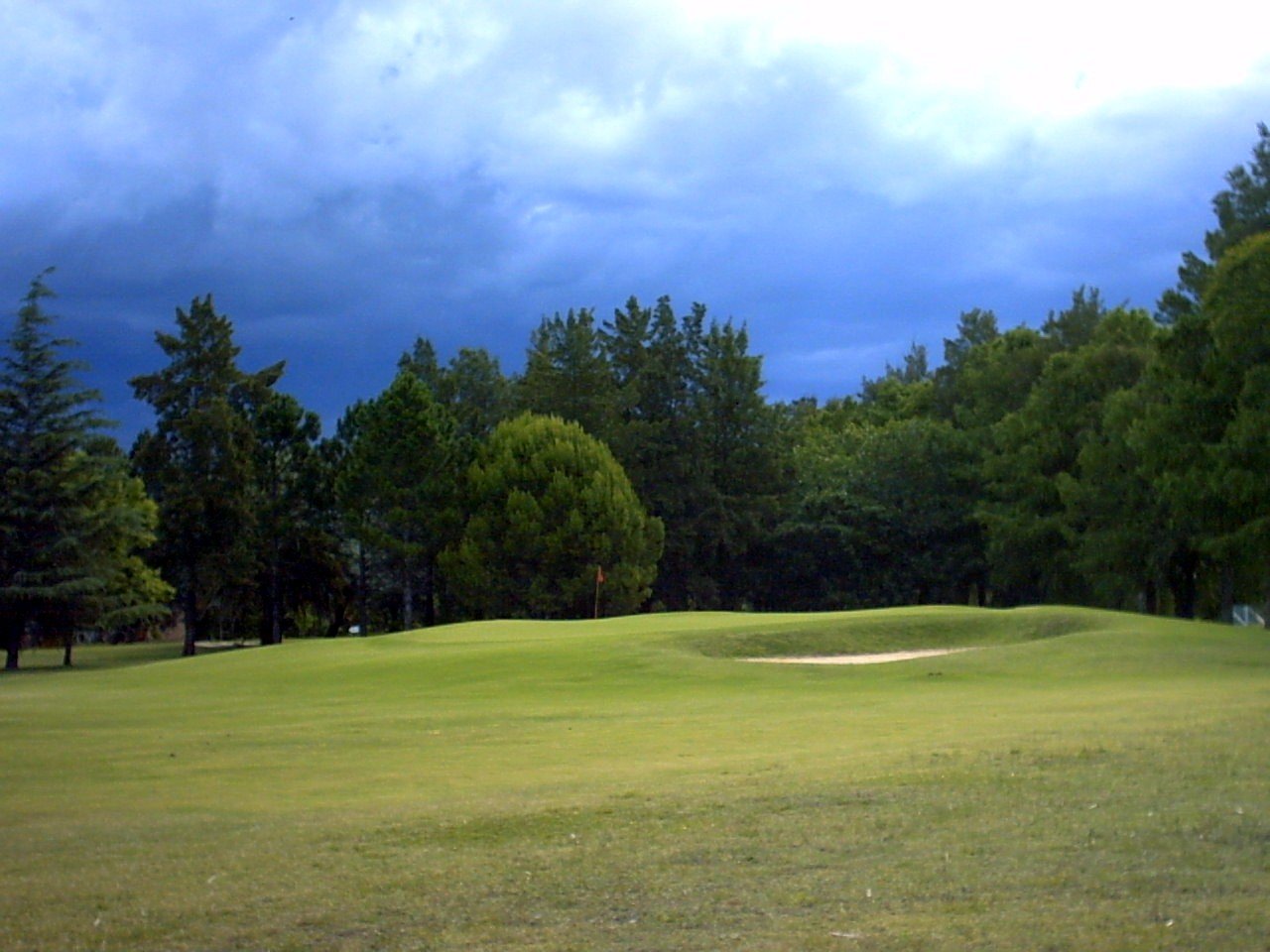 a golf green with the sky in the background