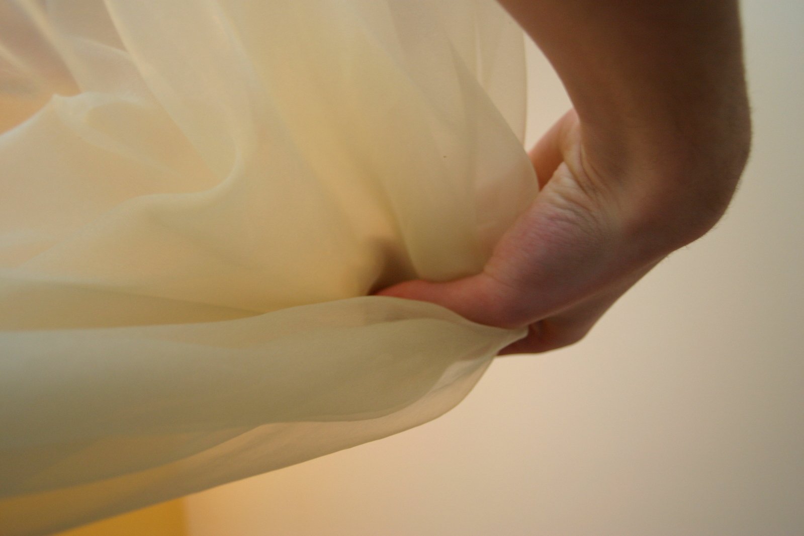 a person reaching down at a bed with white sheets