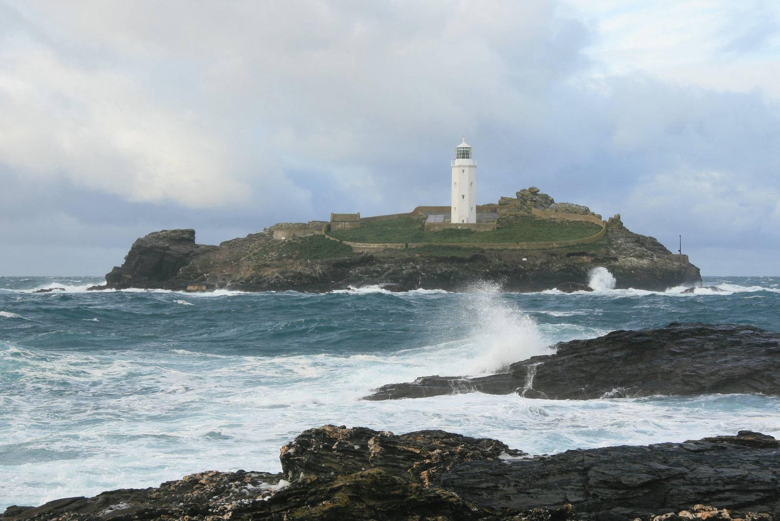 a white lighthouse on the edge of a large body of water