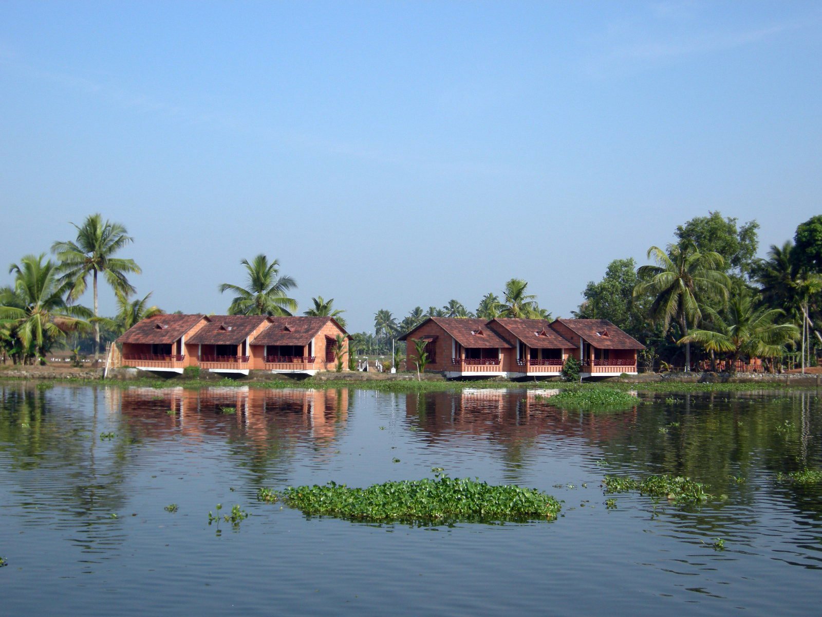 a few brown houses are on the other side of the water