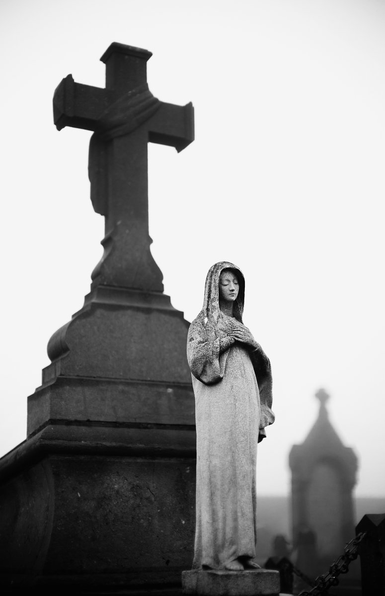 a nun is standing at the cross in a cemetery