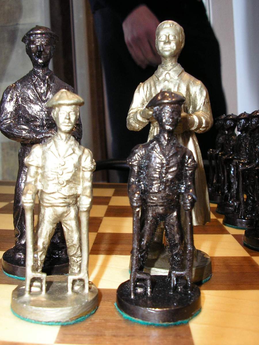 three toy figurines of people and dogs are on a chess board