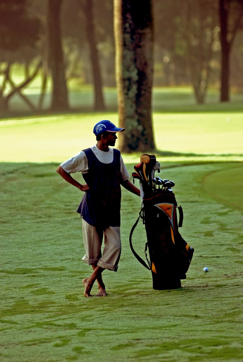 a man in a cap standing next to a golf bag