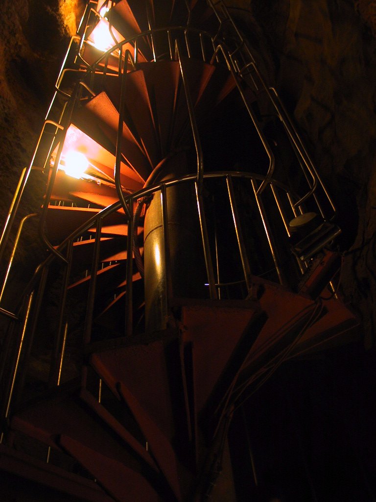 a spiral staircase lit by candles in a cave