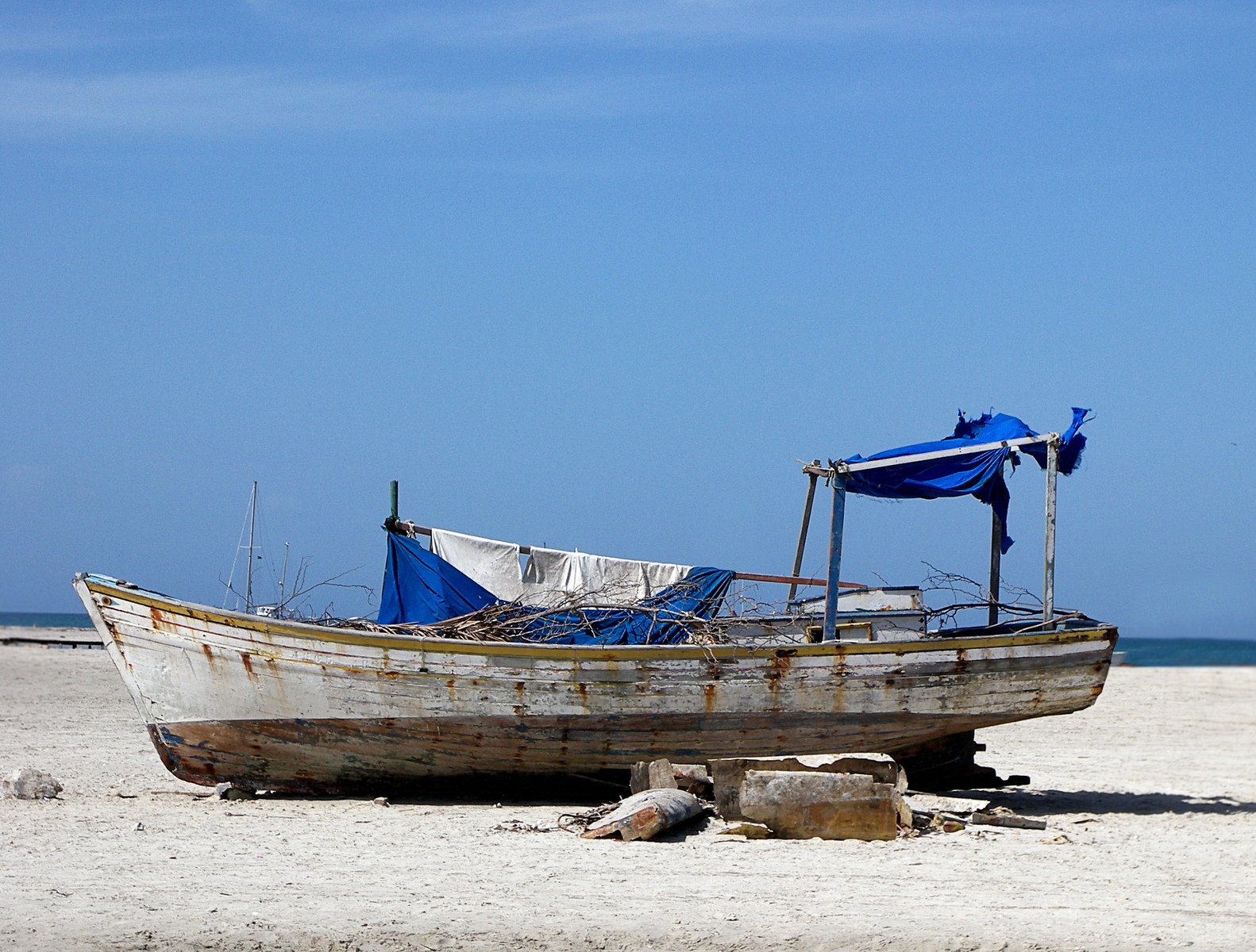 a white boat sitting on top of a sandy beach