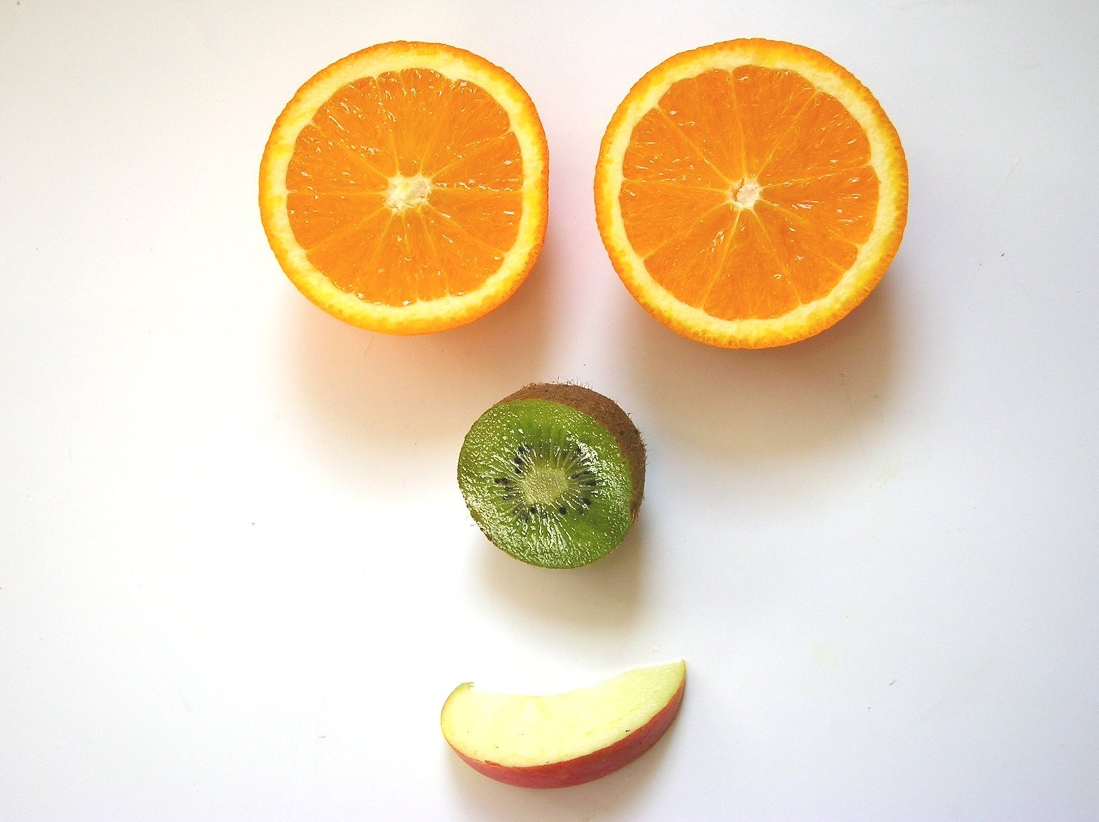 an apple, orange and another piece of fruit are arranged in the shape of a face