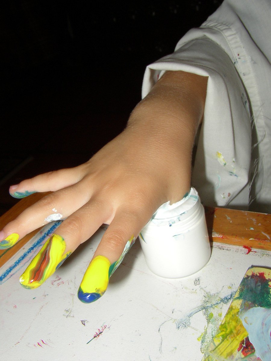 a hand with paint and some paintbrushes sitting on a table