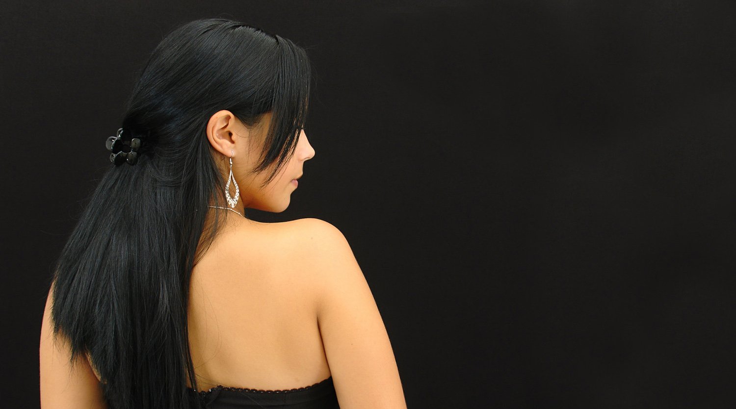 woman with long black ponytail with diamond earrings