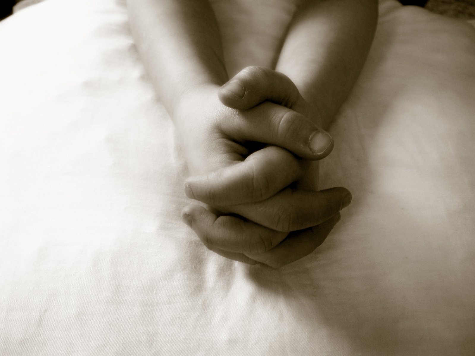 a woman's hands resting on the back of a bed