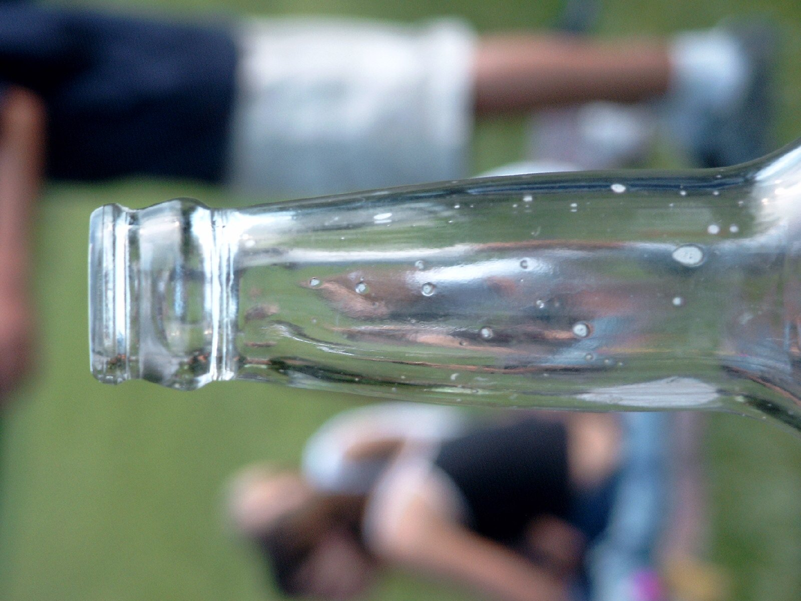 an empty bottle with bubbles sitting on a persons arm