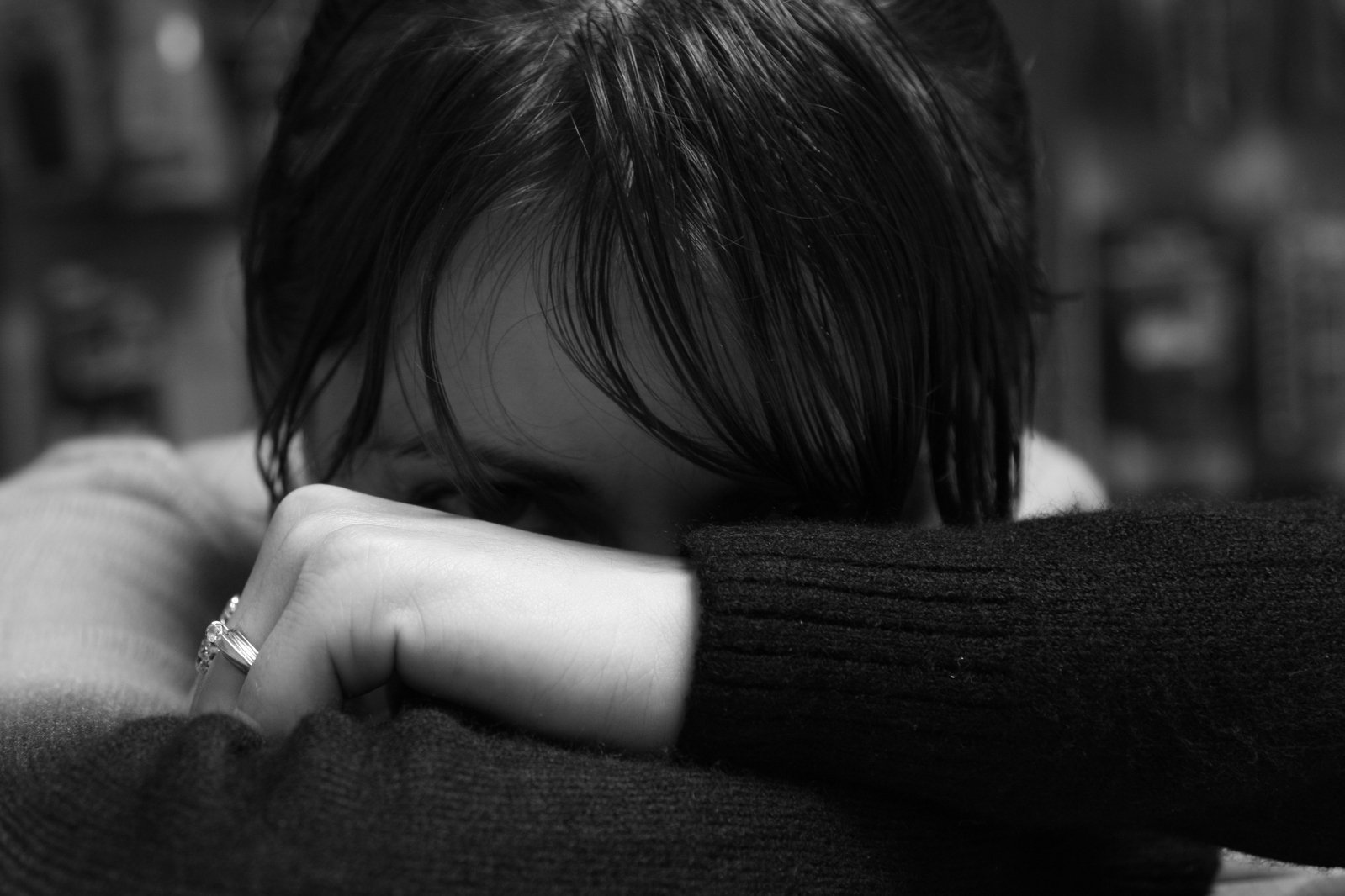 a black and white image of a young woman with a hand on her face