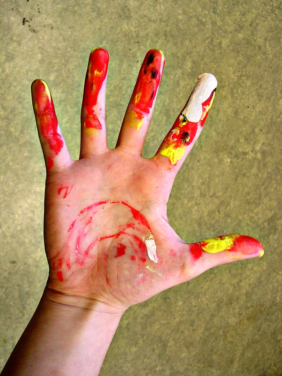 a person is holding up their left hand with their paint splattered on it