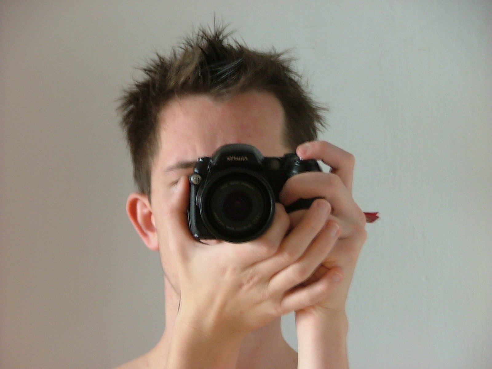 man in a tank top taking pictures with his digital camera