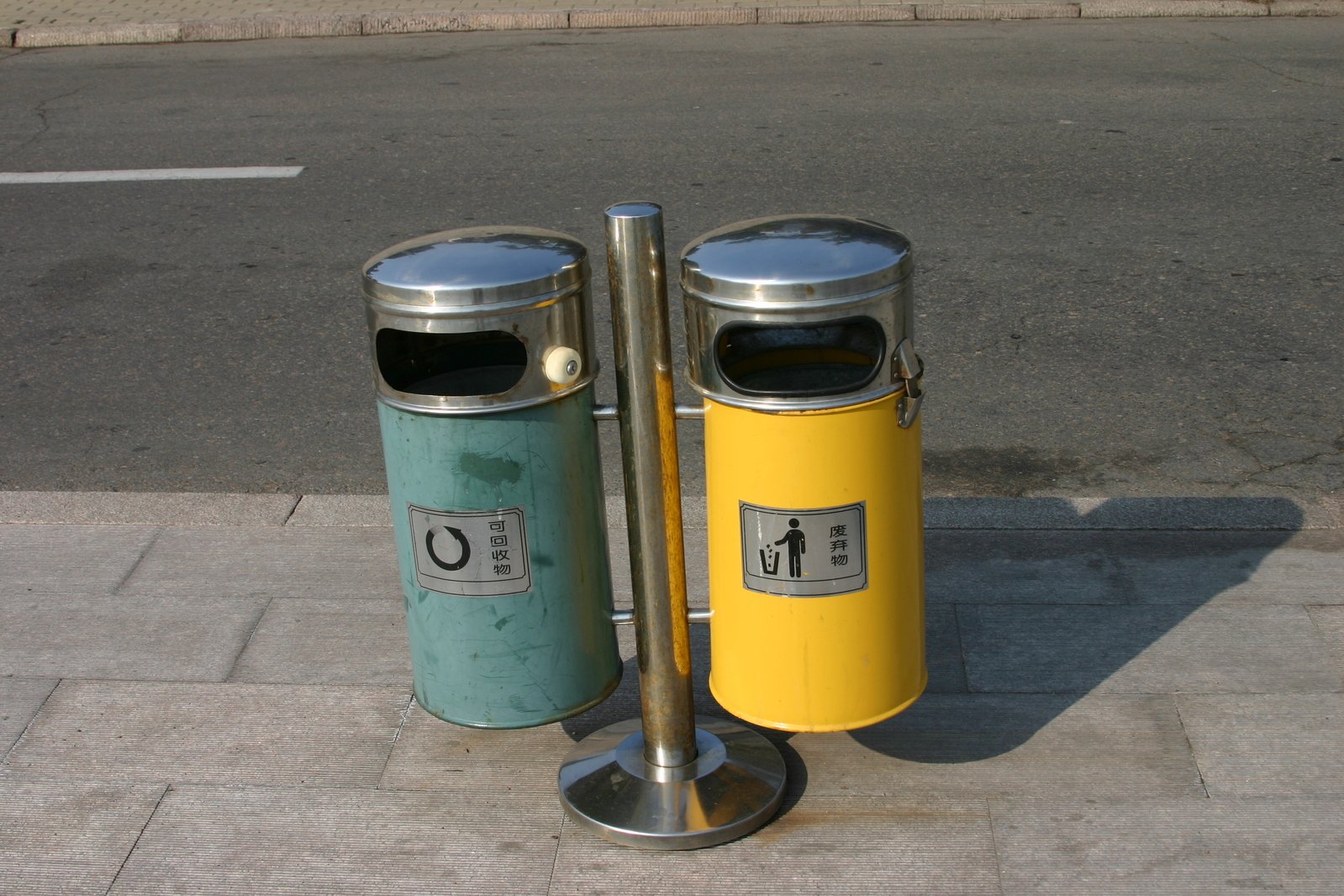 two metal garbage cans are on the sidewalk