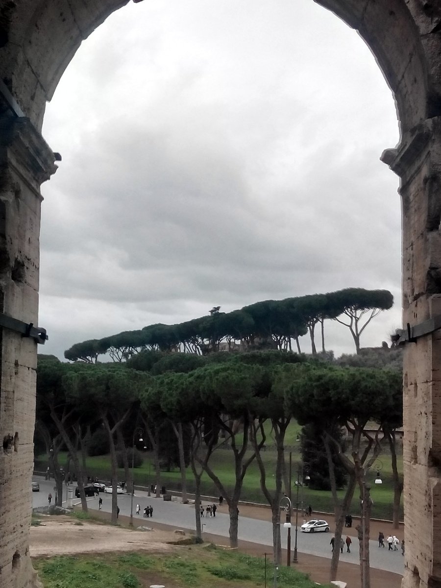 the arch is made of bricks and has lots of trees on top