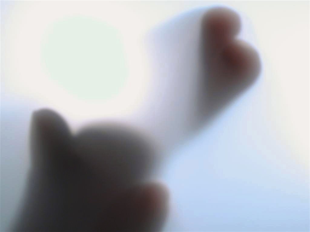 a blurry image of a hand and thumb holding up soing