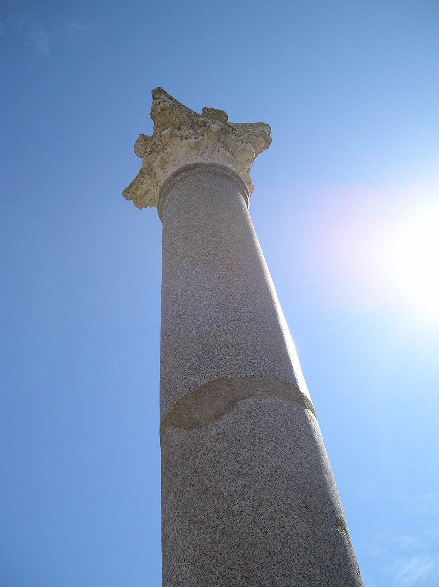 a tall column in the sky with sun in background