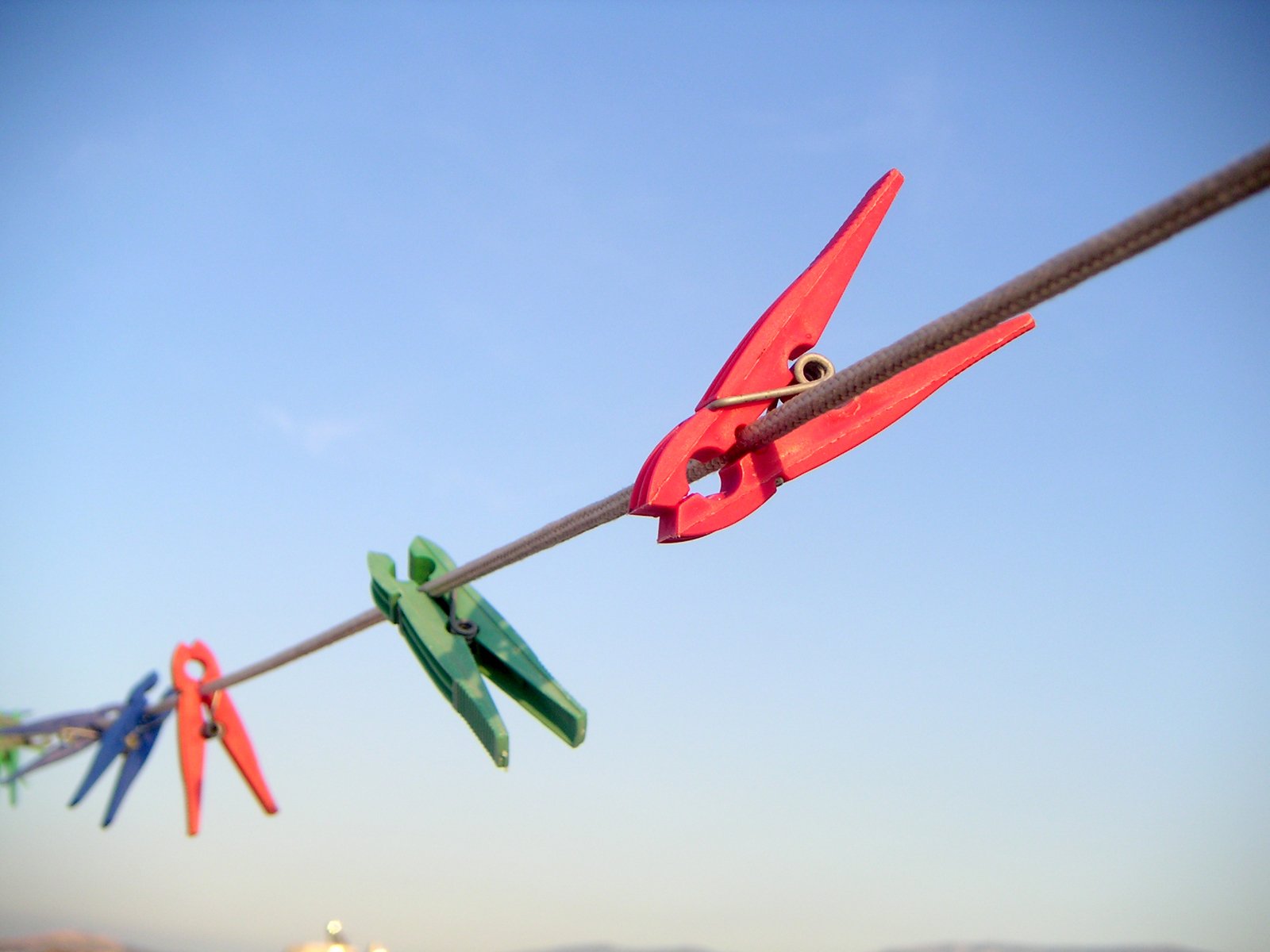 scissors hanging on the line with the sky behind