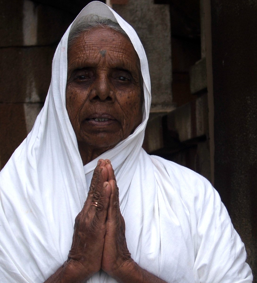 an old woman wearing a white blanket with her hands folded