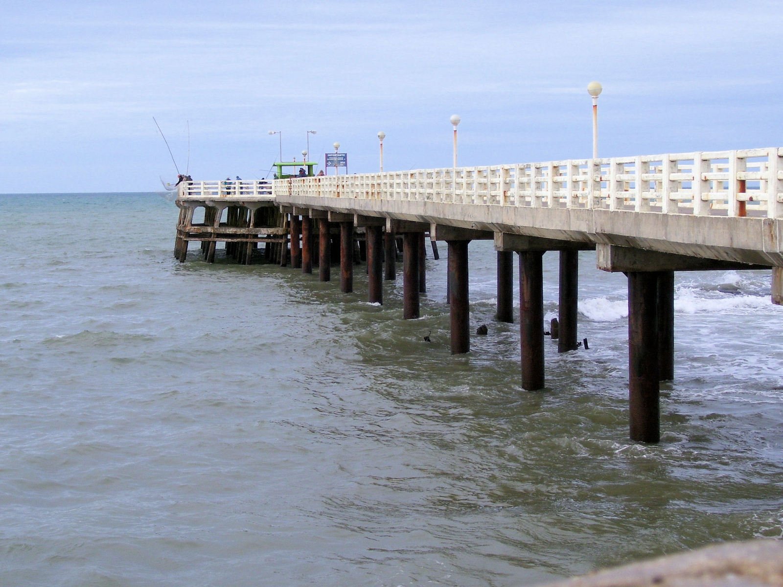 the pier is next to the ocean where people are fishing