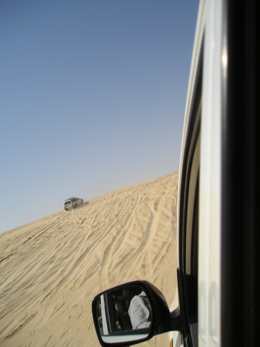 an suv traveling through the desert with snow on top