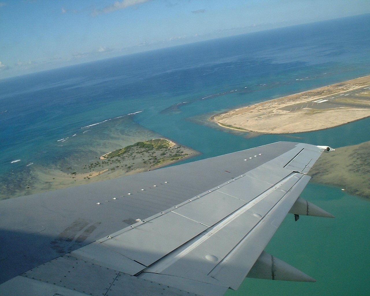 view from airplane window over land, water, and sky