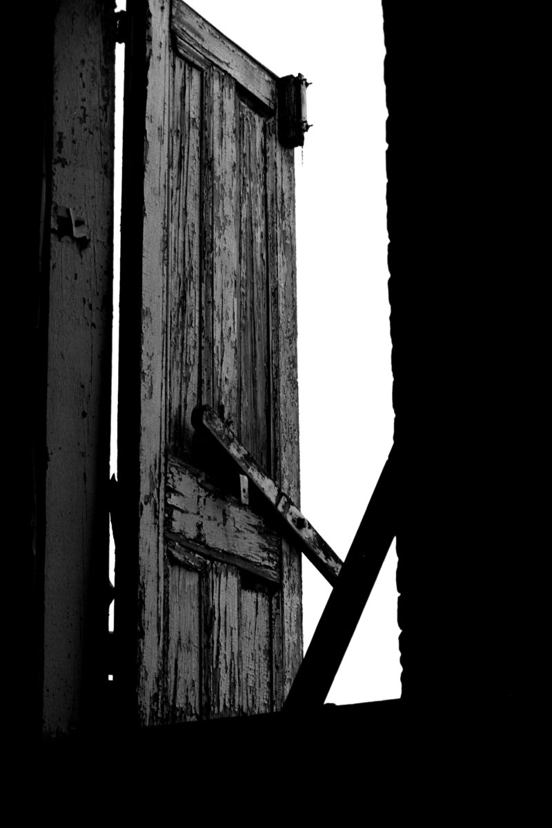 an old door is open against a cloudy sky