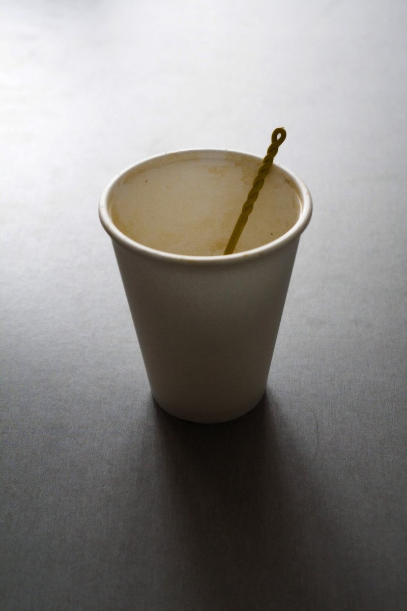 a small cup on a table with a green straw sticking out of it