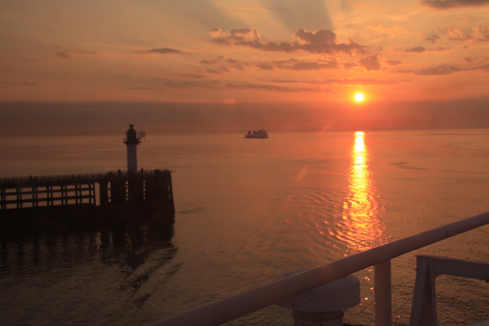 a pier is filled with boats and people on it as the sun sets