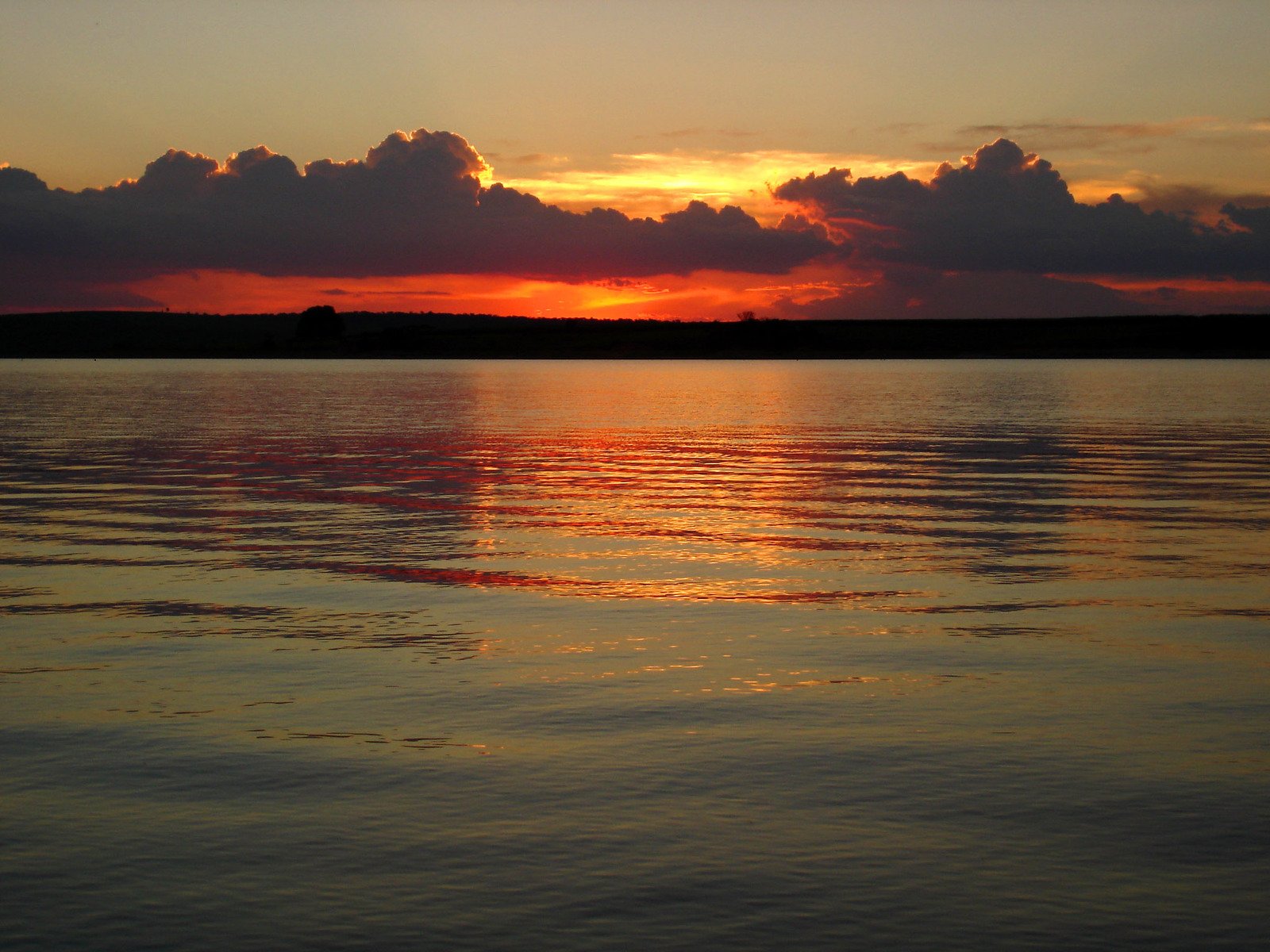 the sun is setting over some lake in the distance