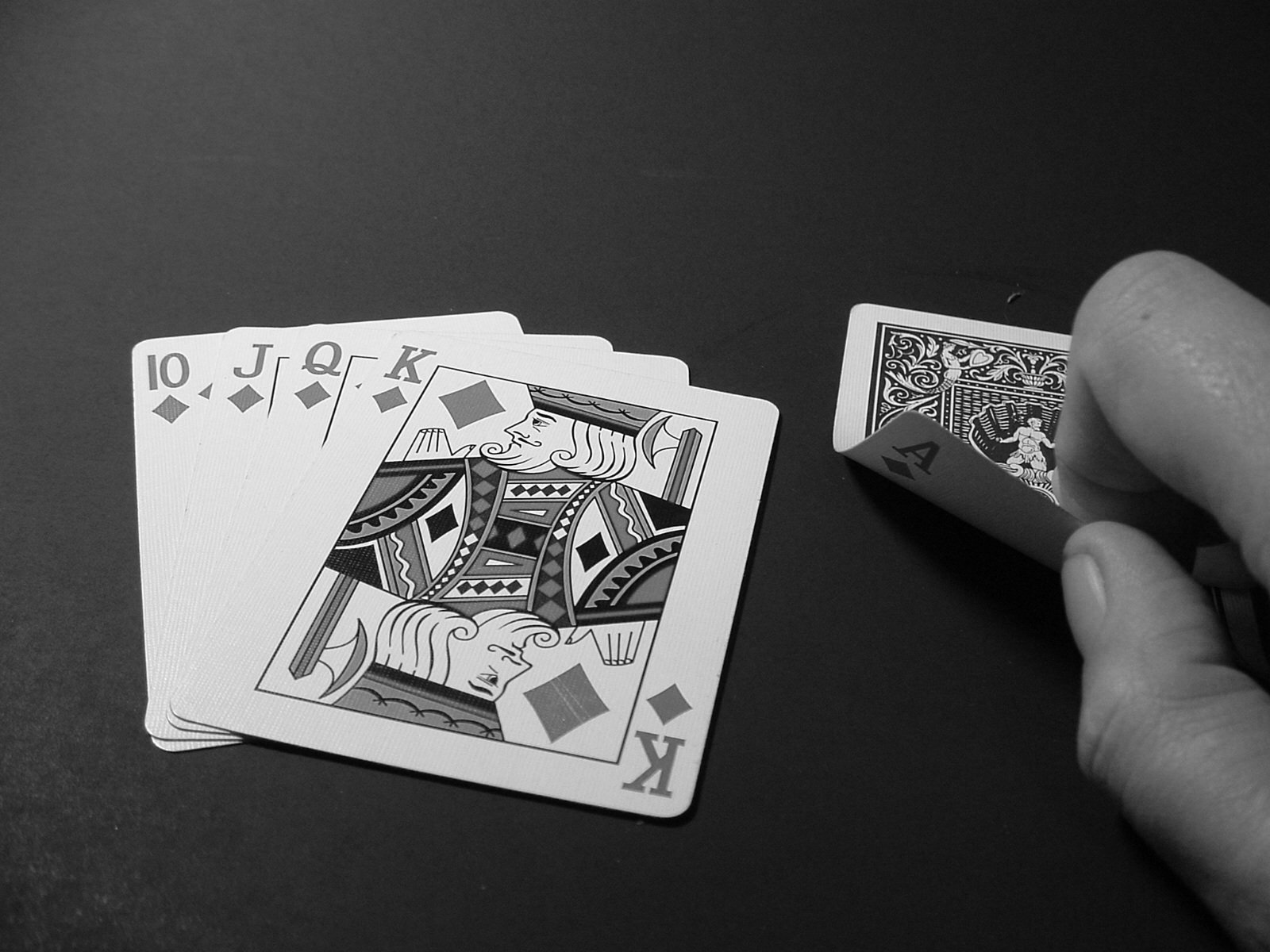a hand holding three playing cards next to an empty one