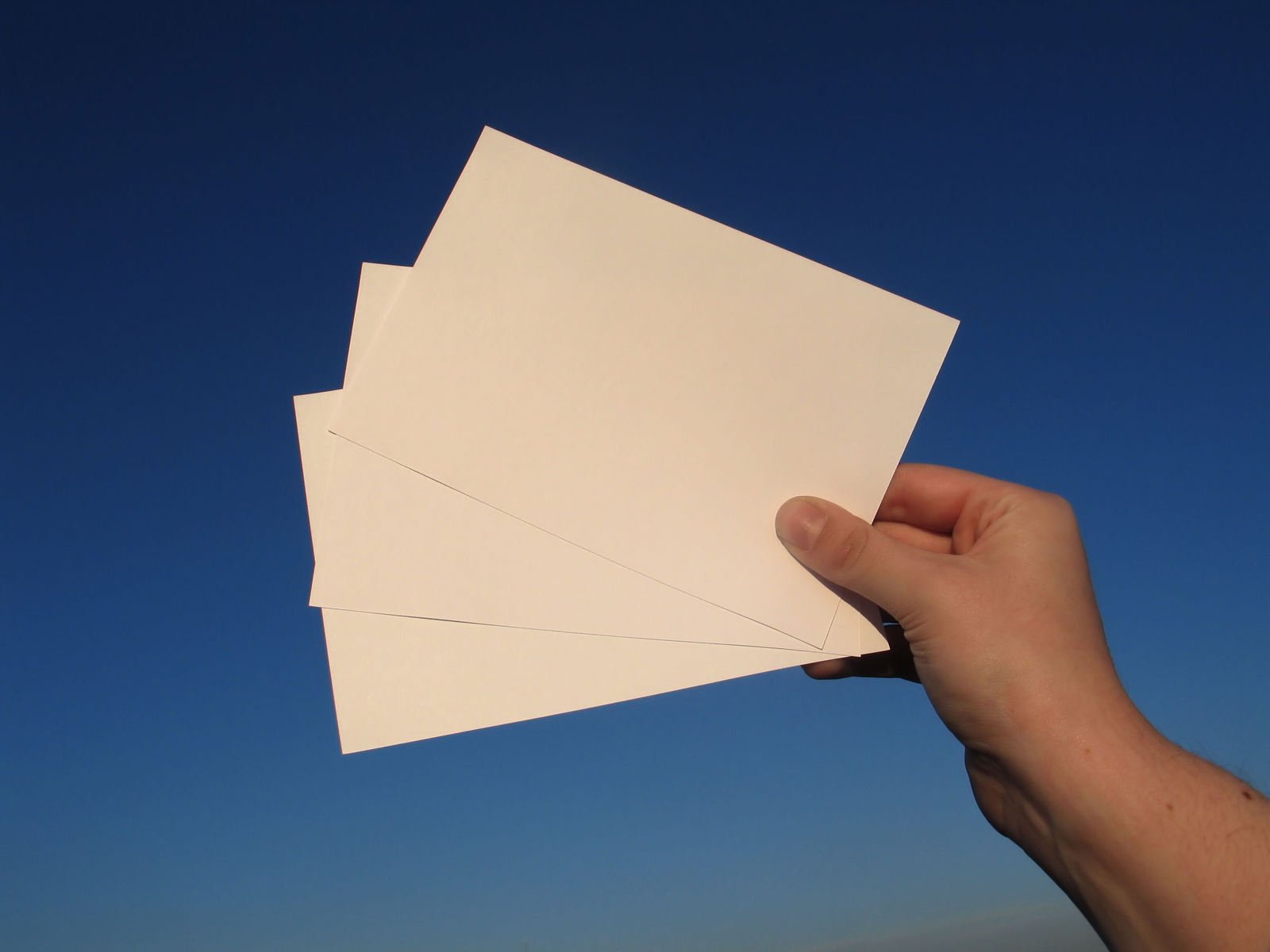 hand holding four cards on blue sky background