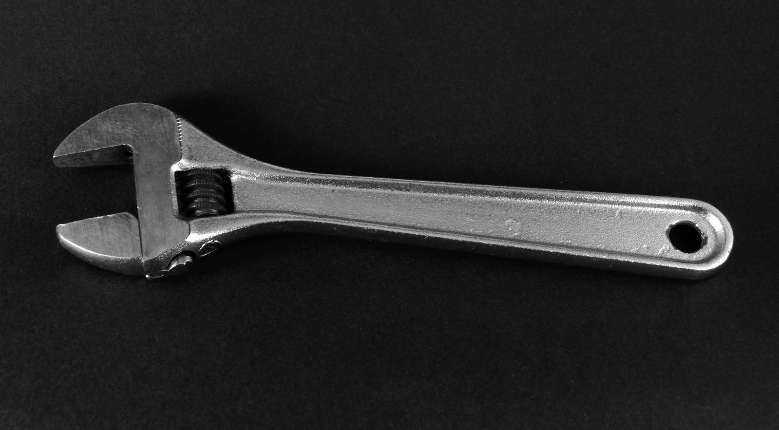 an adjustable wrench on a black background