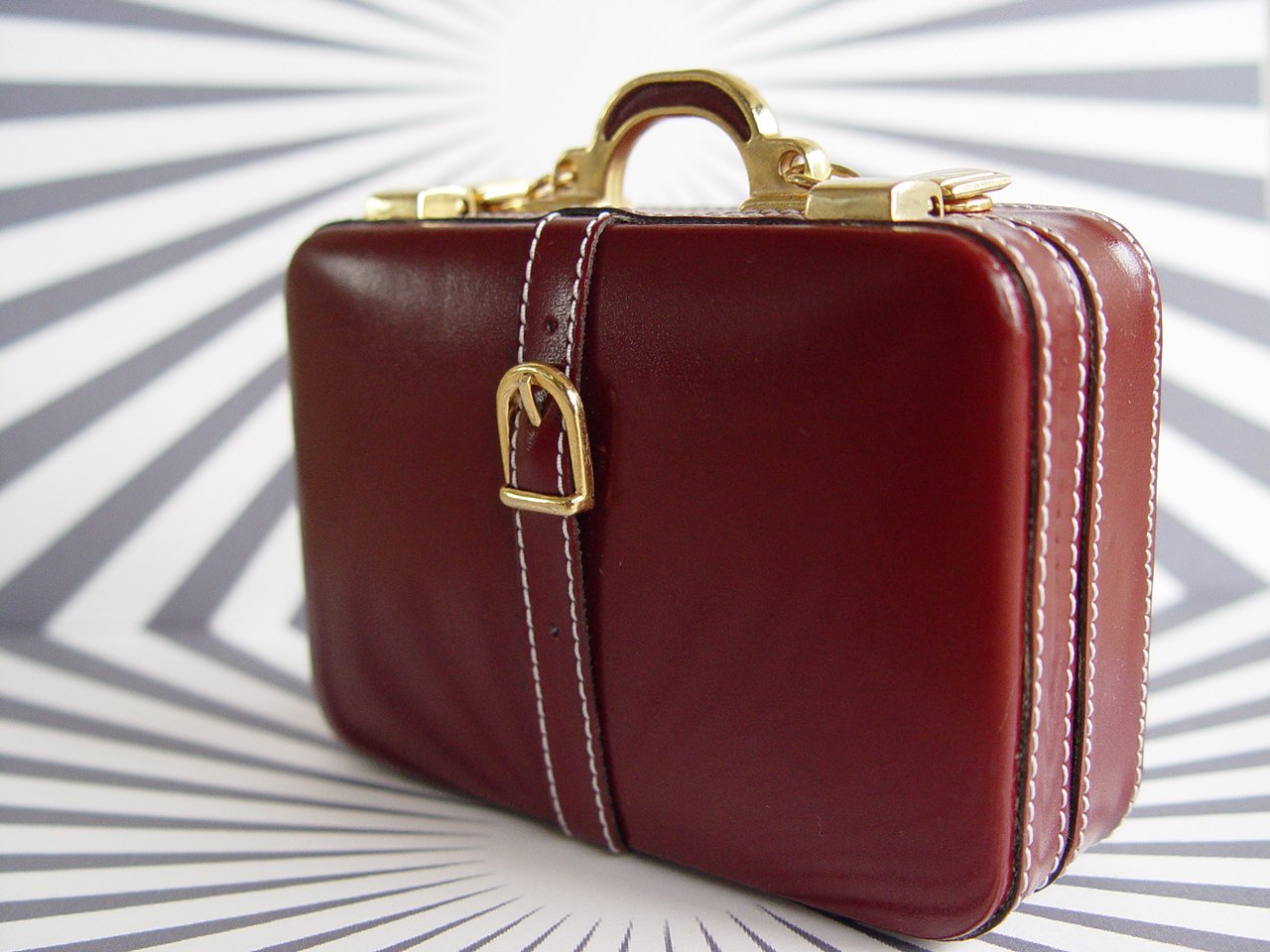 a vintage looking briefcase is on a white and black striped background