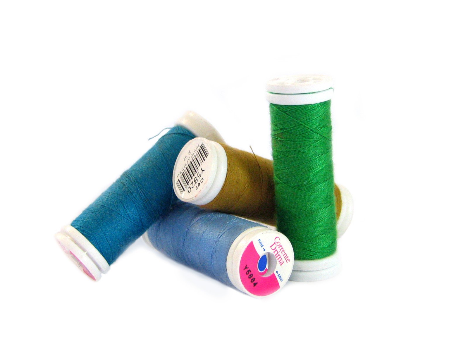 three spools of colorful thread sitting on a white surface