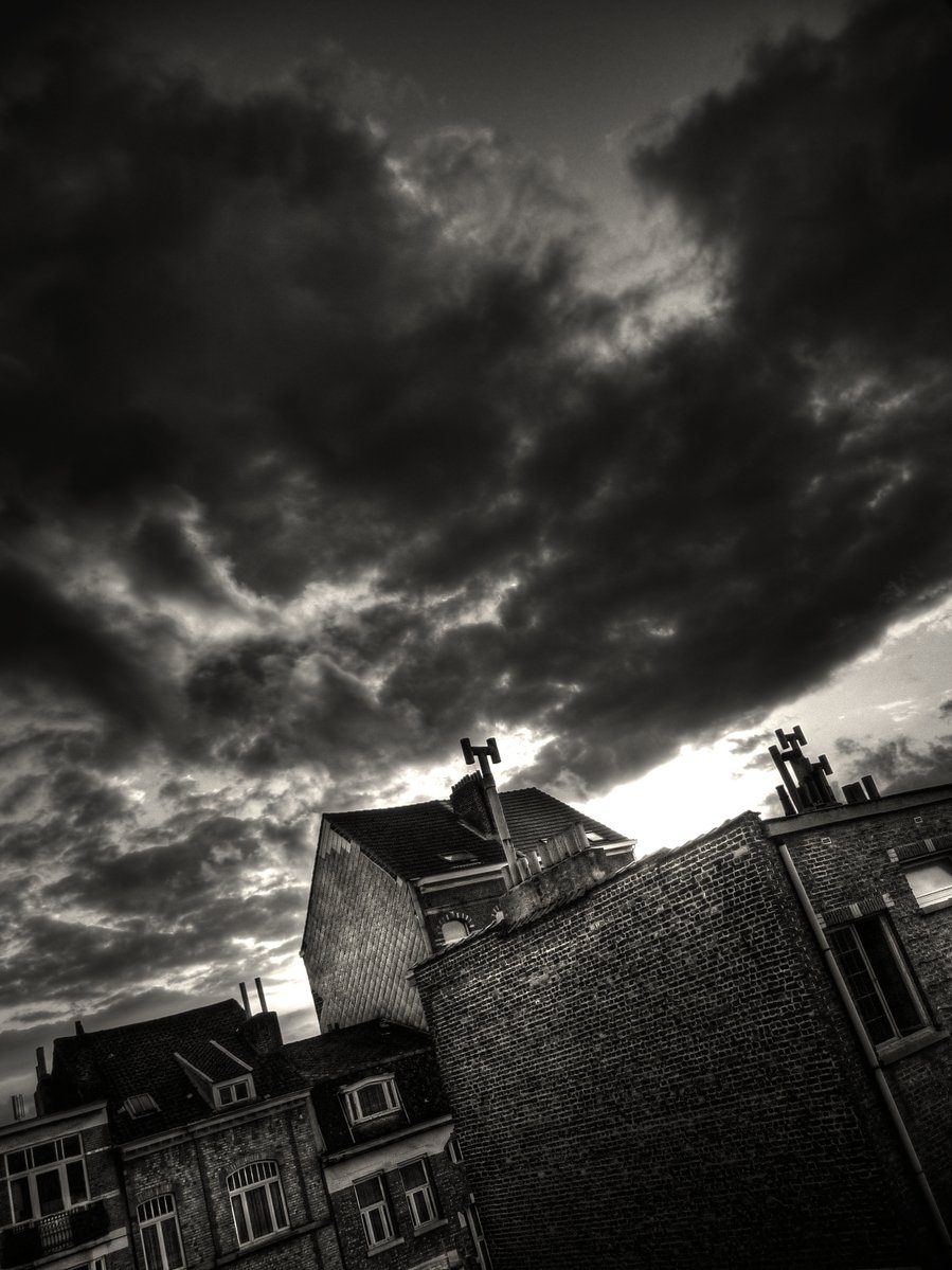 a black and white po of dark clouds over old buildings