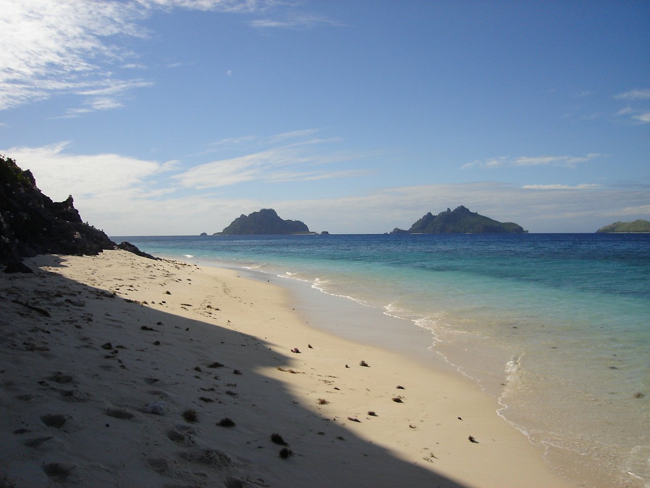 a deserted beach with the ocean and mountains in the distance