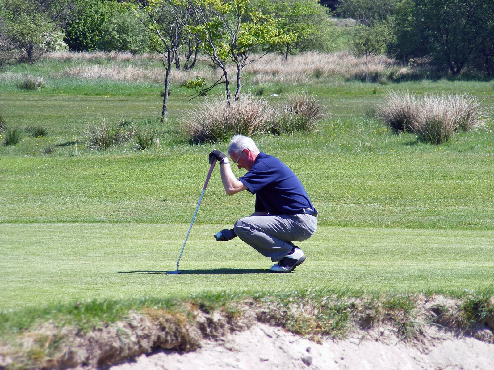 a man who is bent down to hit a golf ball with a club