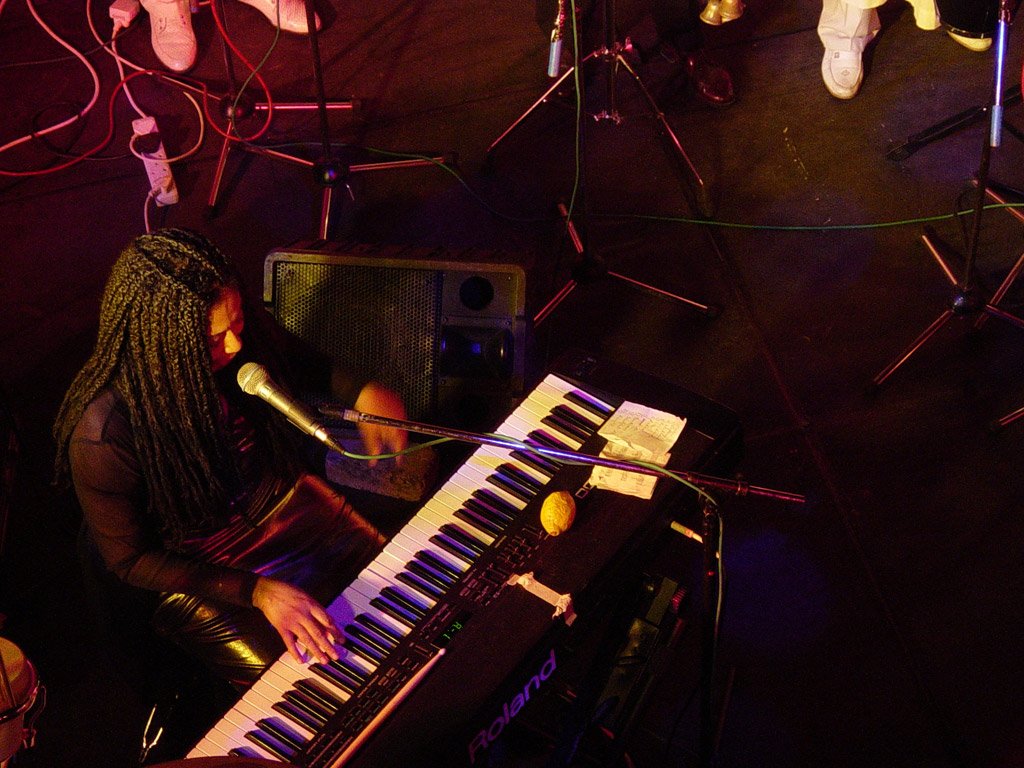 a person sitting at a keyboard with a bunch of wires around her